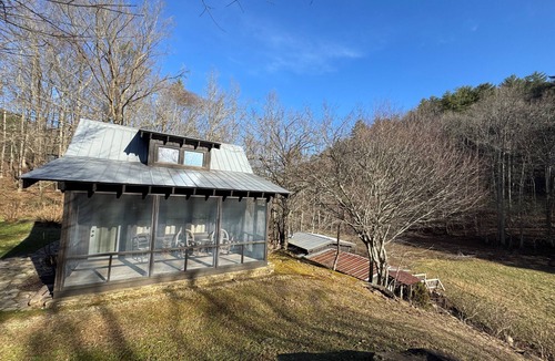 Ellijay Cabin | These charming cabins blend modern design with rustic beauty, offering a peaceful retreat where the main cabin sits one step from a stream, perfect for dining by the water, with stunning views of the surrounding landscape.